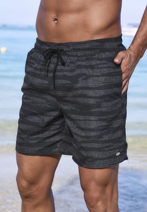 Black swim shorts with a textured striped pattern, elastic waistband, and drawstring. Features side pockets and a small logo on the hem.