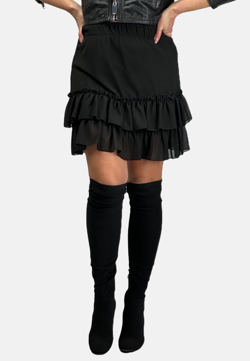 Czarna mini spódniczka z falbanami i elastycznym pasem. Posiada warstwowe falbany i miękki materiał. Połączona z czarnymi skarpetkami do ud.