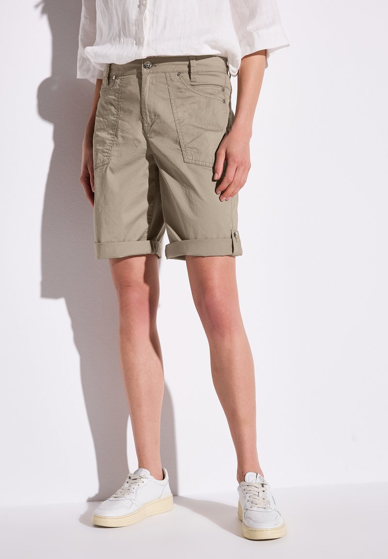 Shorts cargo beiges avec des revers, fabriqués en tissu léger. Comprend des poches des deux côtés et une fermeture à bouton en métal.