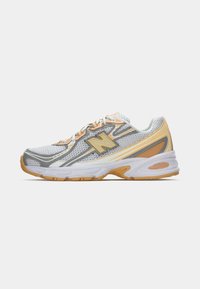 Bela in oranžna tekaška čevlja New Balance z mrežastim zgornjim delom, zavezovanjem in oblazinjeno podplatom označenim kot ABZORB.