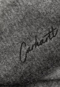 Tela gris texturizada con una superficie suave y difusa. Logo negro "Carhartt" bordado y destacado.