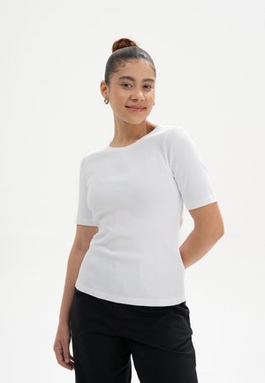 White ribbed knit top with short sleeves, round neckline, and a fitted design, paired with black pants. Simple and versatile styling.