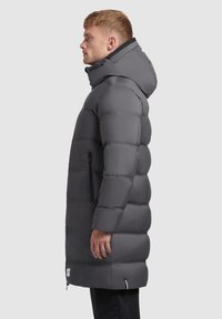 Szary pikowany płaszcz puchowy z kapturem, z obszytymi sekcjami, boczną kieszenią na zamek i minimalistycznym logo na dole. Gładkie, wodoodporne wykończenie.