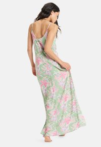 Vestido maxi hecho de tela suave, con una base verde claro y patrones florales en rosa y blanco. Tirantes finos y una silueta fluida.
