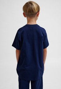 Marineblå bomulds T-shirt med afslappet pasform, korte ærmer og rund halsudskæring, set bagfra. Glat tekstur, enkelt design.