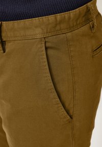 Slim-fit, olive-green pants featuring a smooth texture, side pocket, and detailed stitching along the seams. Ideal for casual wear.