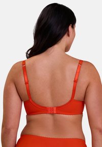 Seno con biancheria intima arancione con spalline regolabili, tessuto testurizzato e schiena liscia. Presenta una chiusura a gancio e occhiello sul retro.