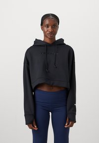 Svart cropped hettegenser med hette, med "NIKE PRO" tekst på forsiden. Kombinert med marineblå høytlivsleggings, lange ermer med mansjetter.