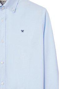 Camicia azzurra chiara a maniche lunghe realizzata in cotone. Presenta un piccolo logo ricamato blu notte, colletto button-down e bottoni bianchi. Tessuto liscio.