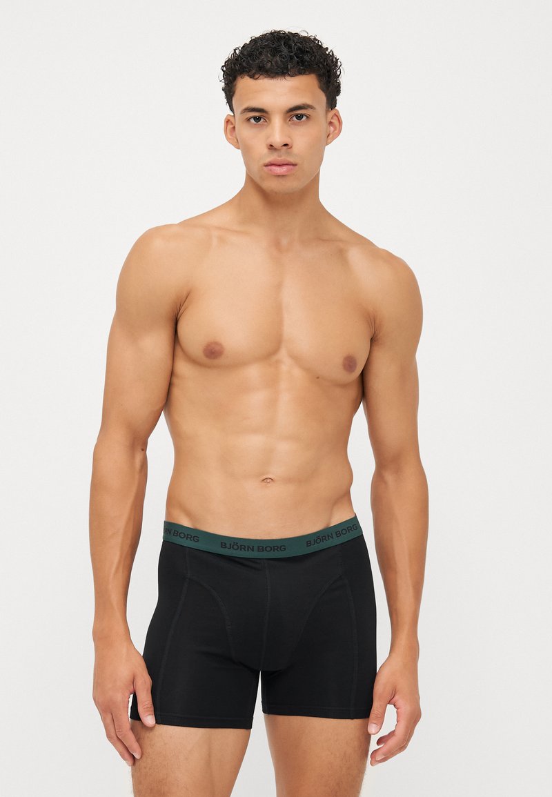 Boxer brief neri con un elastico verde BJÖRN BORG, caratterizzati da un design aderente e una texture liscia. Il modello mostra la vista frontale.
