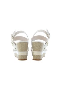 Vita klacksandaler med strukturerad tygklack och justerbart ankelsnöre. Har en guldlogotyp på sidan och en slät läderöverdel.