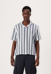 Camisa de manga corta, abotonada, con rayas azul y blanca alternas; la tela parece texturada con un corte holgado y cuello.