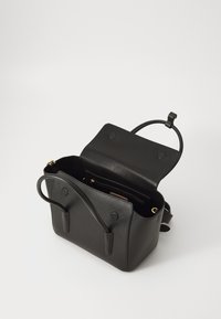 Sac à main en cuir noir avec une finition texturée, une poignée supérieure unique et une fermeture magnétique. Il possède une poche zippée intérieure et un espace ouvert.