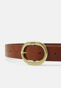Ceinture en cuir marron avec une grande boucle ovale en laiton portant le logo "Levi's", plusieurs perforations pour le réglage et une texture lisse.