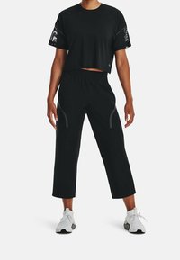 Black cropped t-shirt with short sleeves and mesh details, paired with black cropped pants featuring reflective accents and an elastic waistband.