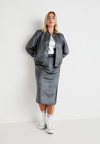 Grå faux suede bomberjakke med trykknapper, kombinert med et matchende blyantskjørt med sideslitt. Brukt med hvite sneakers.
