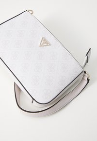 White textured handbag with a logo pattern, black trim, and a triangular metal logo accent. Features a detachable strap.