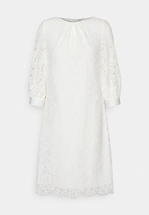 Hvid knælængde blondekjole med trekvartlange pufærmer, bølget kant og en lille frontplissering under den runde halsudskæring.