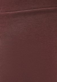 Bordeaux leggings gemaakt van gladde, rekbare stof. Heeft een hoge tailleband en een naadloos ontwerp voor comfort en flexibiliteit.