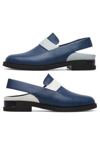 Mocassins slingback en cuir bleu avec détail de sangle blanche et semelle noire, montrés en profil latéral sous des angles gauche et droit.