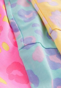 Tre campioni di tessuto mostrano una stampa leopardata pastello. I colori includono rosa, verde menta e giallo, con texture morbide e lisce e motivi delicati.