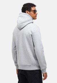 Felpa grigia con un grande cappuccio, polsini e bordo a coste. Realizzata in materiale morbido, con una texture liscia e una vestibilità comoda.