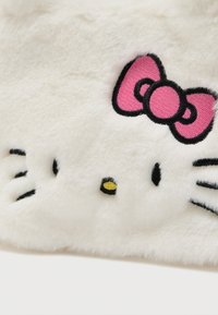 Fehér plüss anyag, Hello Kitty arcát ábrázoló mintával, rózsaszín masnival. Fekete hímzett bajusz és szemek, sárga orr. Simogató tapintású.