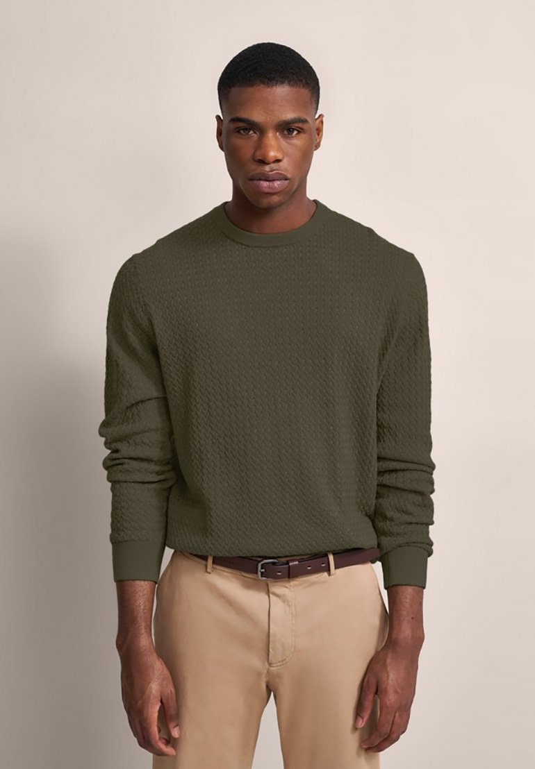 Maglione lavorato a maglia verde oliva con un motivo testurizzato, colletto e polsini a costine, abbinato a pantaloni beige e una cintura marrone.