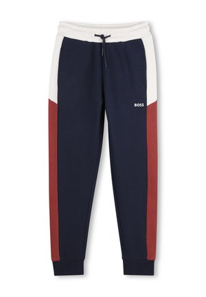 Jogging bleu marine avec ceinture blanche et bandes latérales blanches et rouge rouille, avec un cordon noir et un petit logo BOSS blanc.