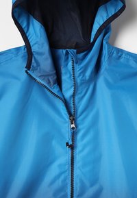 Blauwe hooded jacket met een zwarte ritssluiting die gedeeltelijk open is, waardoor de zwarte mesh voering binnenin de capuchon zichtbaar is.