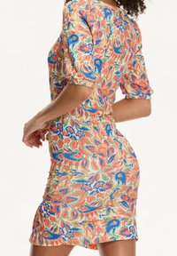 Robe imprimée fleurie avec une silhouette ajustée, des manches courtes bouffantes et des motifs multicolores en orange, bleu et vert sur un fond clair.