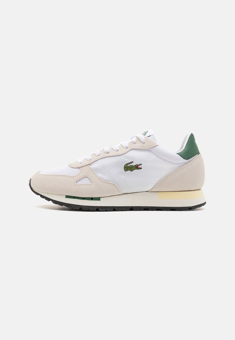 Sneakers med en beige semsket overdel og en hvit syntetisk overdel, grønn hæloks og en grønn krokodillelogo. Gummisåle med svart grep.