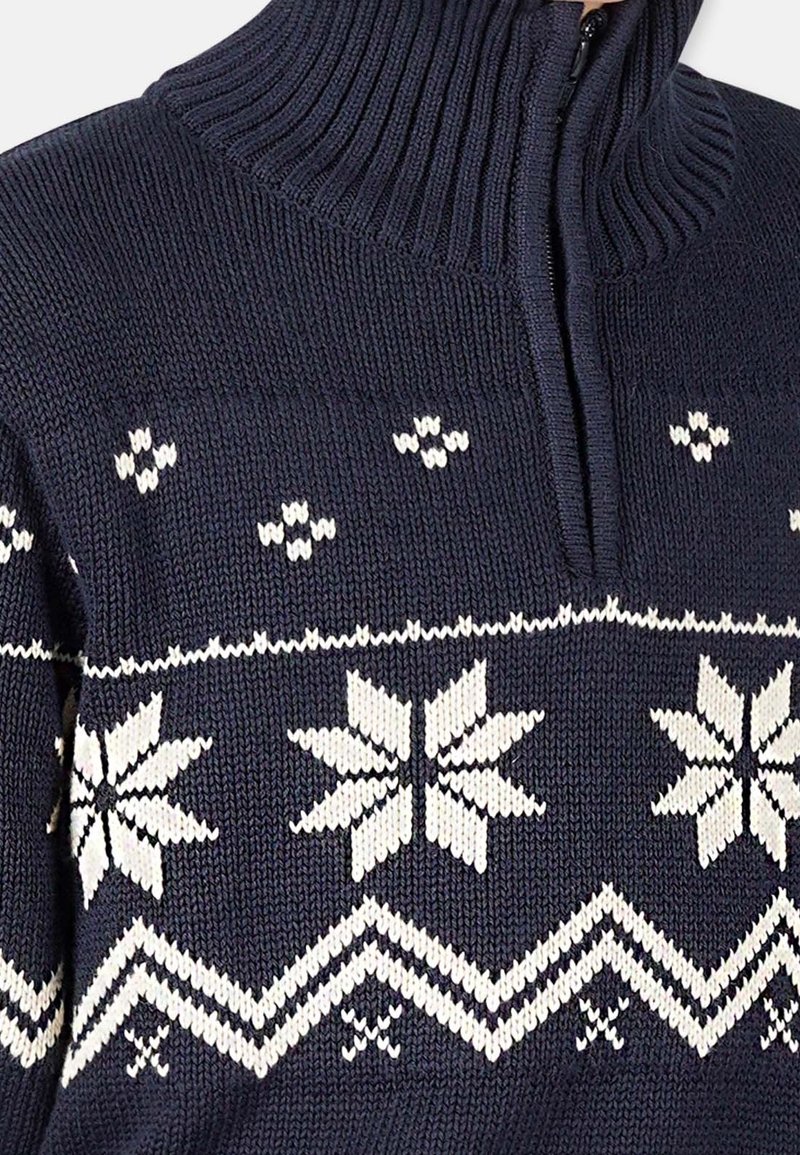 Pull en maille bleu marine avec motifs flocons de neige blancs et une fermeture éclair partielle sous un col montant côtelé.
