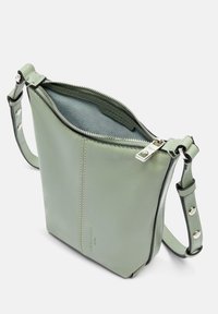 Kleine grüne Ledertasche mit Reißverschluss, einem einstellbaren Tragegurt und einem kontrastierenden hellblauen Innenfutter. Glatte Textur, minimalistisches Design.