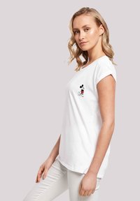 Biała koszulka t-shirt z krótkim rękawem wykonana z bawełny, z czarno-czerwonym wzorem Myszki Mickey na lewej piersi. Gładka faktura, swobodny krój.