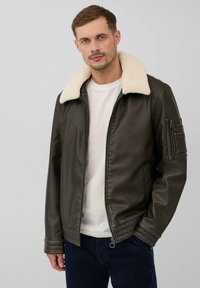 Dunkelgrüne Kunstlederjacke mit einem cremefarbenen Sherlingkragen, Reißverschluss und seitlichen Taschen. Verfügt über eine Tasche am linken Ärmel.