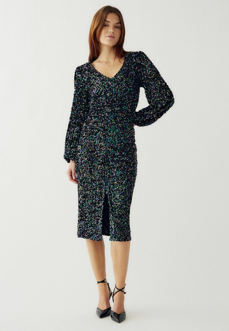 Blizgučių suknelė su V formos iškirpte, ilgomis pūstomis rankovėmis ir kelių ilgio hemu. Yra centrinė plyšio detalė, juoda bazė su spalvotais perlo blizgučiais.