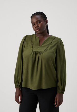 Groene blouse met lange mouwen en een v-hals, voorzien van gathered mouwen en een gestreepte textuur. Afgewerkt met borduursel langs de halslijn.