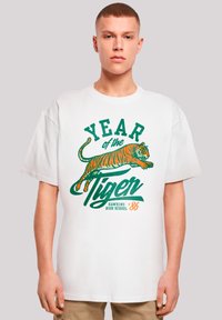 White cotton T-shirt featuring an orange and green tiger graphic, with "YEAR of the TIGER" and "HAWKINS HIGH SCHOOL '86" text.