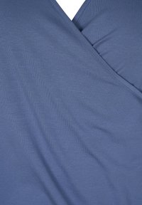 Blå inwrapt topp i mjukt, stretchigt tyg med V-ringning, som har en slät yta och subtil ribbstruktur.
