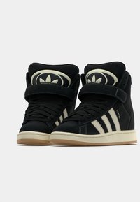 Μαύρα sneakers υψηλού πάτου με σουέτ υφή, που διαθέτουν τρεις κρεμ ρίγες, επενδεδυμένο περιλαίμιο στον αστράγαλο και λογότυπο στη γλώσσα.