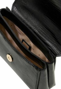 Sac à main en simili cuir noir à texture crocodile, avec une fermeture à pression dorée et deux compartiments doublés en tissu beige.