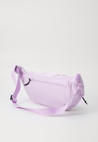 Marsupio lilla realizzato in nylon morbido, dotato di una tasca frontale con zip, tracolla regolabile, forma arrotondata e texture liscia.