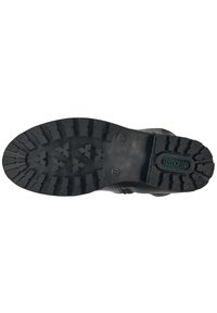 Semelle en caoutchouc noir d'une chaussure avec un motif texturé, présentant des rainures et des crêtes profondes pour une adhérence optimale. Logo "remonte" visible sur le talon.