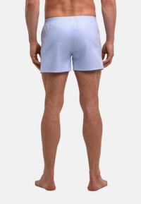 Lichtblauwe zwembroek met een elastische tailleband, gemaakt van gladde stof. Korter dan de knie, met een klassiek ontwerp zonder zichtbare patronen.