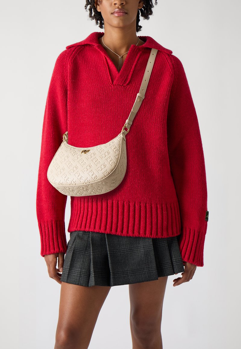 Rdeča pletena pulover s V-izrezom in rebrastim robom, v kompletu s bež usnjeno torbo z embosiranim logotipom in ravnim naramnim trakom.