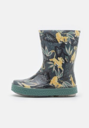 Børns regnstøvle, der går til midt på læggen, med mørk baggrund, grøn struktureret sål og et mønster af gule tegneserieleounger og grønne blade.