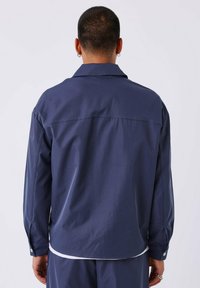 Donkerblauwe overhemd met lange mouwen, een klassieke kraag, knoopmanchetten en een gladde textuur. Heeft een rechte snit en een minimalistisch ontwerp.