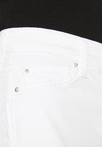 Calças de ganga brancas em denim com uma textura suave, detalhes em metal prateado e um bolso frontal. O design inclui um estilo clássico de cinco bolsos.