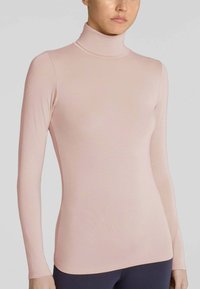 Maglietta a maniche lunghe con collo alto in rosa chiaro, realizzata in un tessuto morbido ed elastico. Presenta una forma aderente e dettagli di cucitura minimi.
